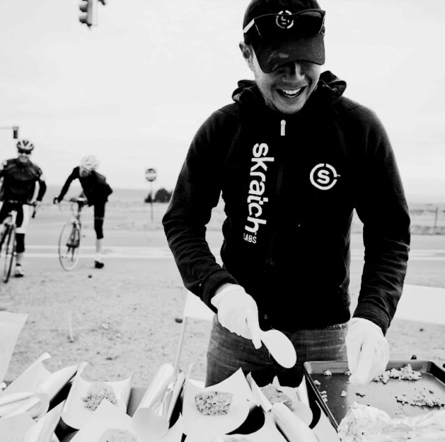 A Skratch Labs staffer preparing real-food snacks at the roadside as riders pass